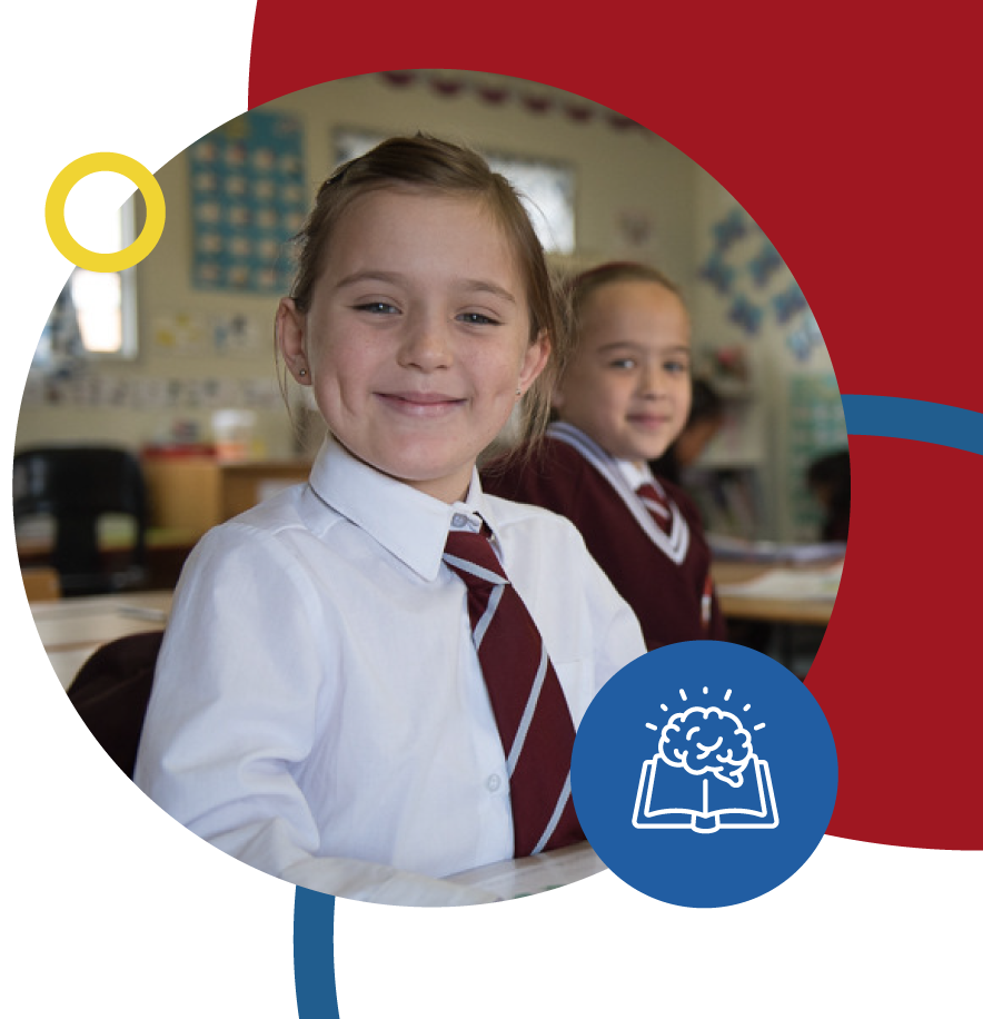 A Happy Riverside College primary school learner sitting at her desk in her classroom